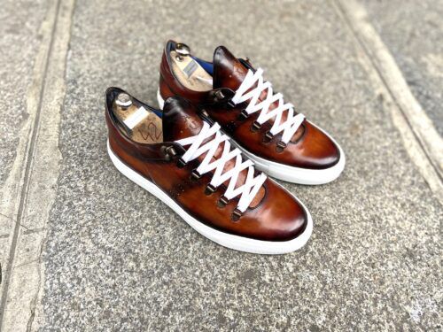 des baskets pour homme en cuir à tannage végétal sans chrome de couleur cognac posent sur le bitume