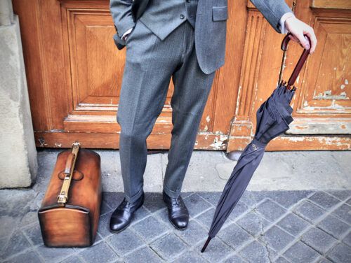 Un homme au costume impeccable pose avec une paire de richelieus noirs Caulaincourt élégants